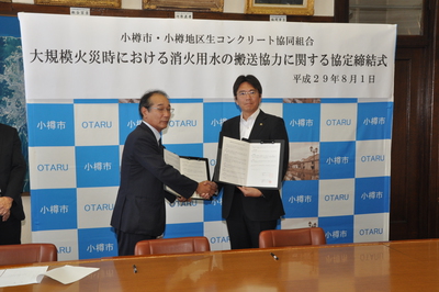 小樽地区生コンクリート協同組合田中理事長と小樽森井市長が協定書に調印後、握手