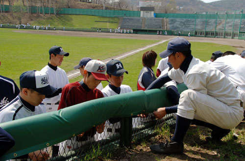 高校球児が桜ヶ丘球場の金網フェンスに防護マットを設置